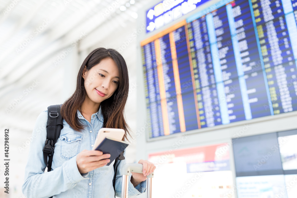 Fototapeta premium Young woman checking her flight on cellphone