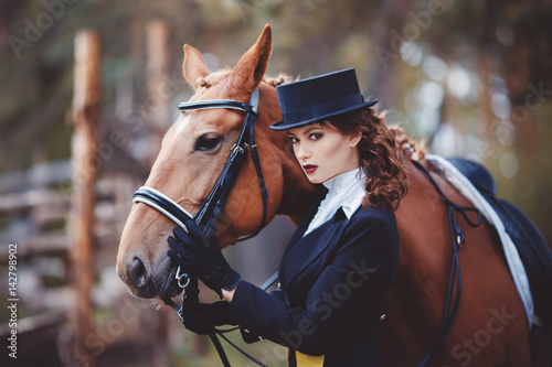 arge portrait, riding, the concept of advertising equestrian club. Jockey girl in a suit scratches a horse. © Parilov