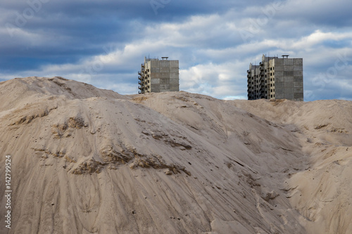 Unfinished multi-storey houses look out from behind sand dunes