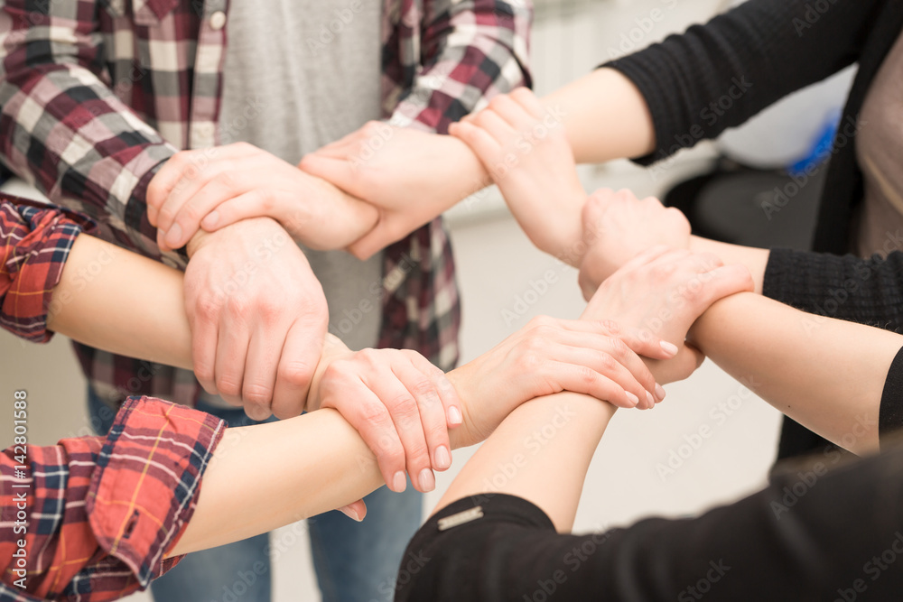 A group of young people hold strong hands.
