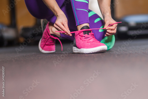 Young woman tying shoelaces in the gym
