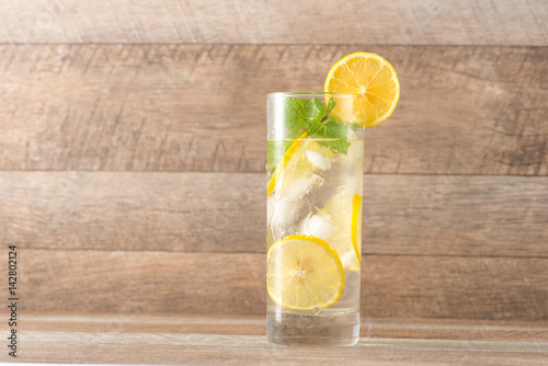 Drink for hot summer days. Fresh lime and lemon lemonade with mint in a glass on a wooden desk