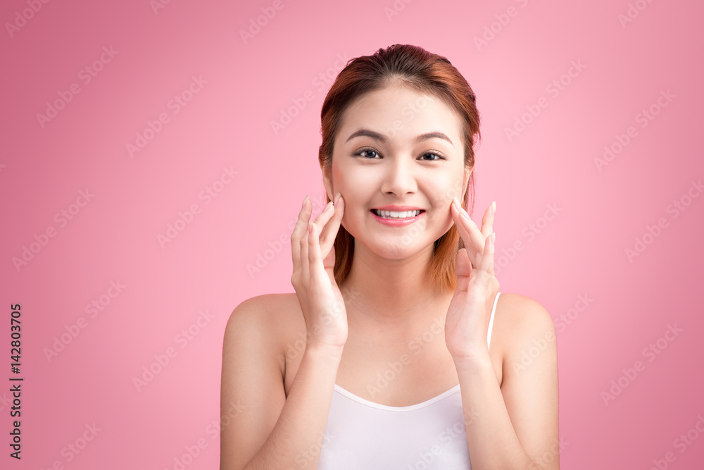 Young asian woman touching her perfect skin, isolated on pink background