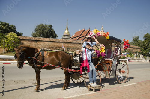 Travelers thai women posing with horse drawn carriage before tour around city at Wat Phra That Lampang Luang