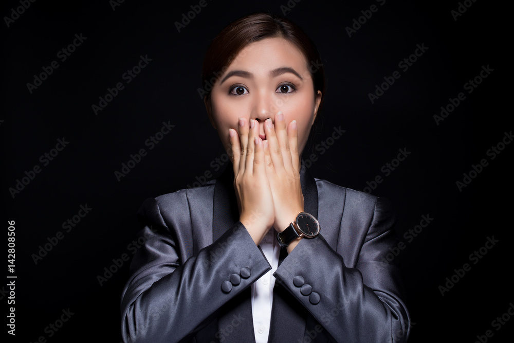 Businesswoman in black suit has surprise on dark background Businesswoman in black suit has surprise on dark background
