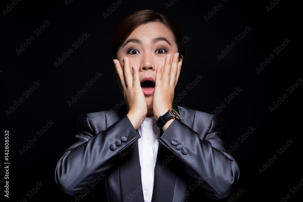 Businesswoman in black suit has surprise on dark background Businesswoman in black suit has surprise on dark background