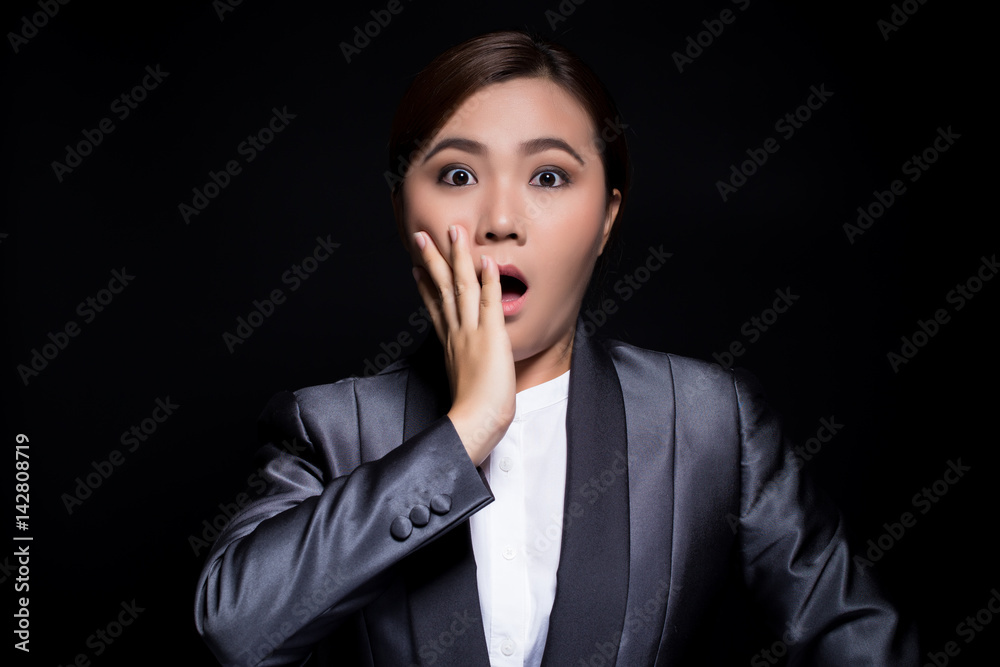 Businesswoman in black suit has surprise on dark background Businesswoman in black suit has surprise on dark background