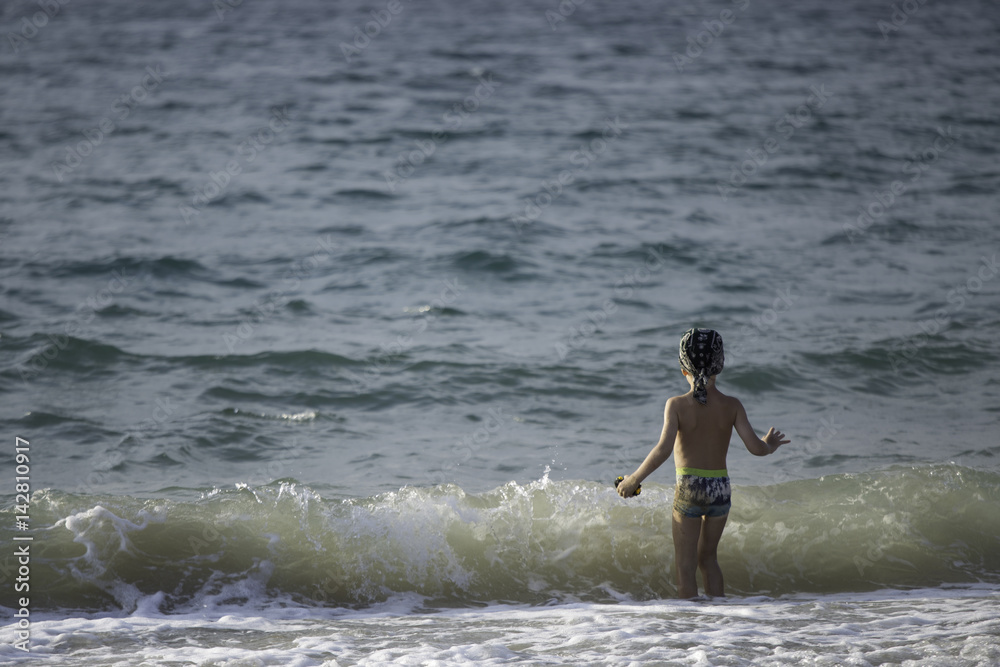 Fototapeta premium A boy playing sea water and wave on the beach