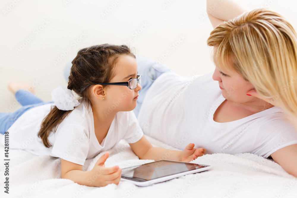 mother and baby are looking to play and read tablet computer on the couch at home mother and baby are looking to play and read tablet computer on the couch at home