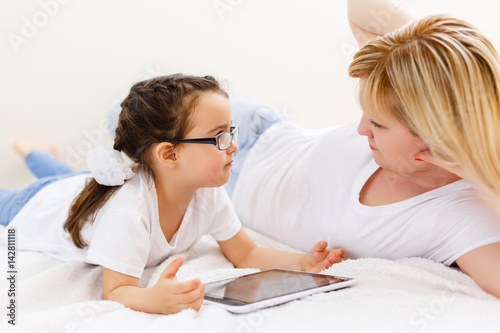 mother and baby are looking to play and read tablet computer on the couch at home © Angelov