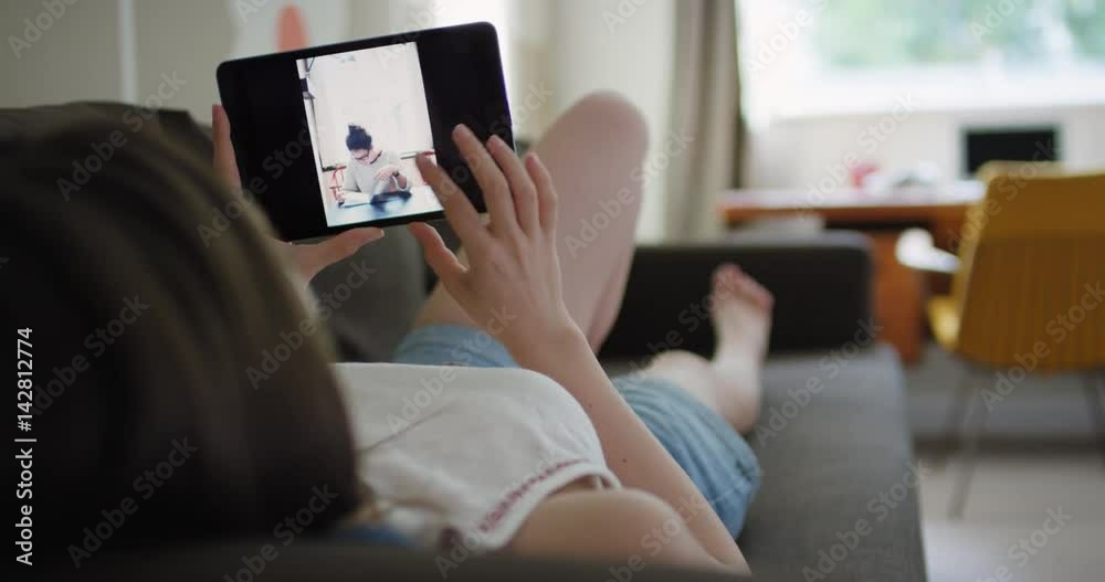 Closeup of Woman using digital tablet in retro styled home lying on sofa viewing travel photos on touch screen browsing social media sharing wanderlust inspiration on digital device