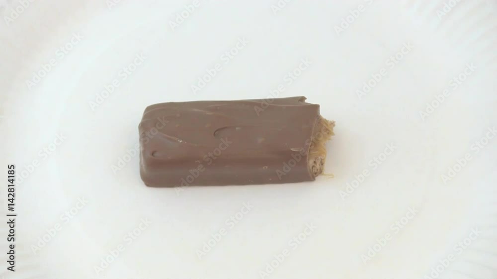 Large chocolate bar decreases in size as it gets eaten on a plain white paper plate. Large chocolate bar decreases in size as it gets eaten on a plain white paper plate.