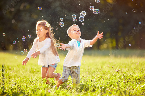 Cheerful children chase bubbles