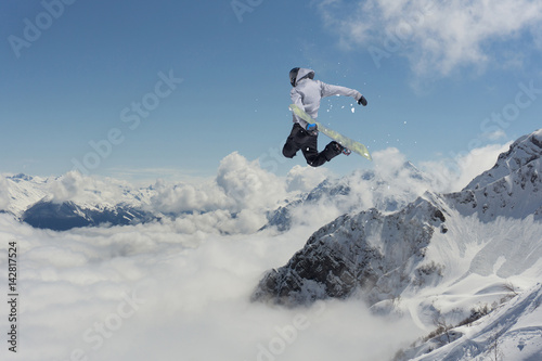 Snowboarder jumps in mountains, winter extreme sport.
