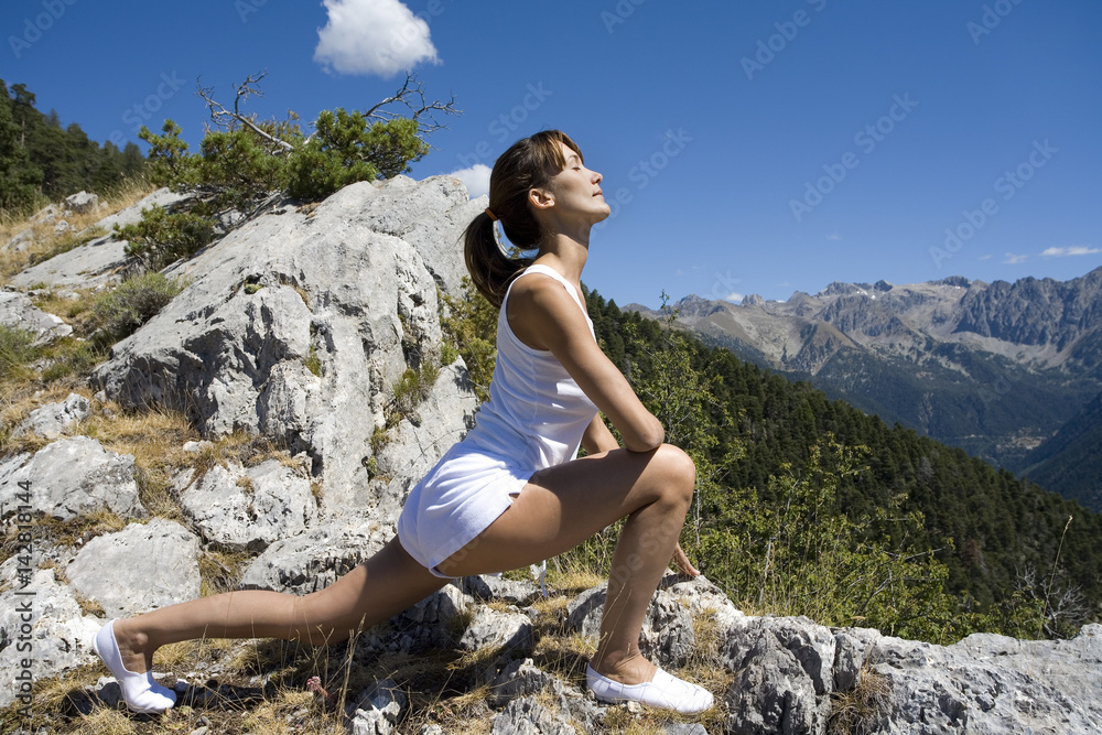 femme en montagne en été qui fait du stretching  au soleil 