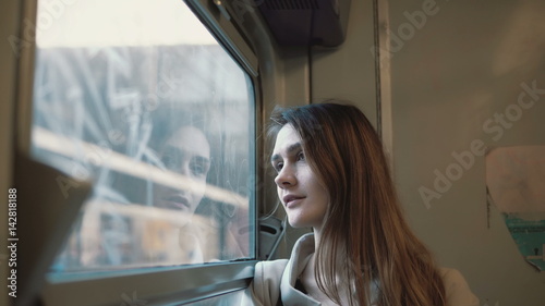 Young beautiful woman traveling by train. Attractive girl looking at window and exploring the landscape outside.