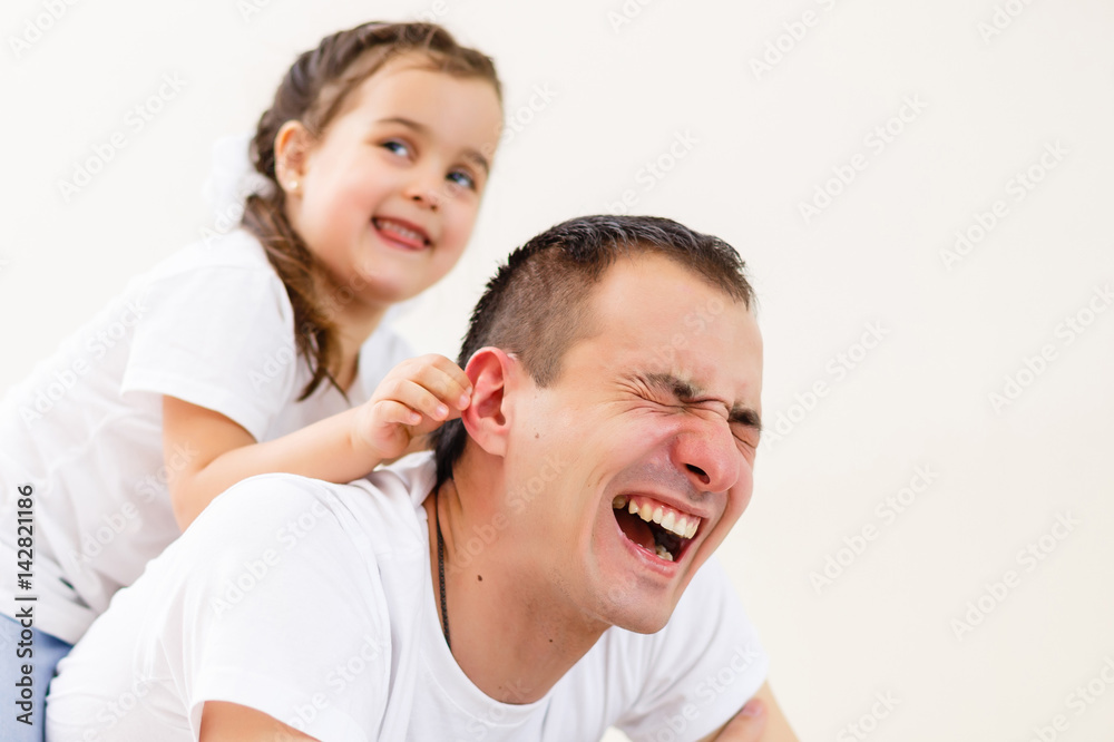 Smiling father carrying on his shoulders his little daughter isolated on white background Smiling father carrying on his shoulders his little daughter isolated on white background