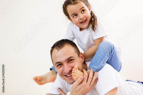 Smiling father carrying on his shoulders his little daughter isolated on white background