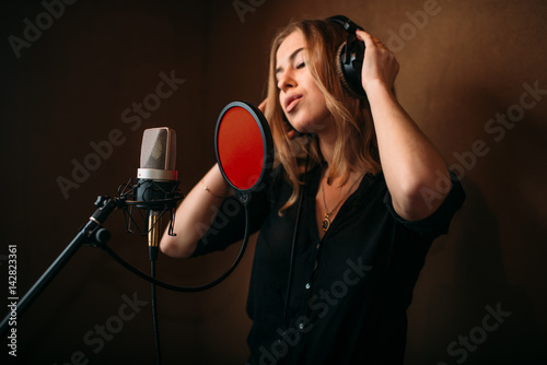 Φωτογραφία Female singer in headphones against microphone