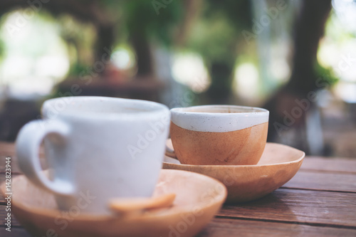 Two cups of hot coffee on vintage wooden table with blur nature background 