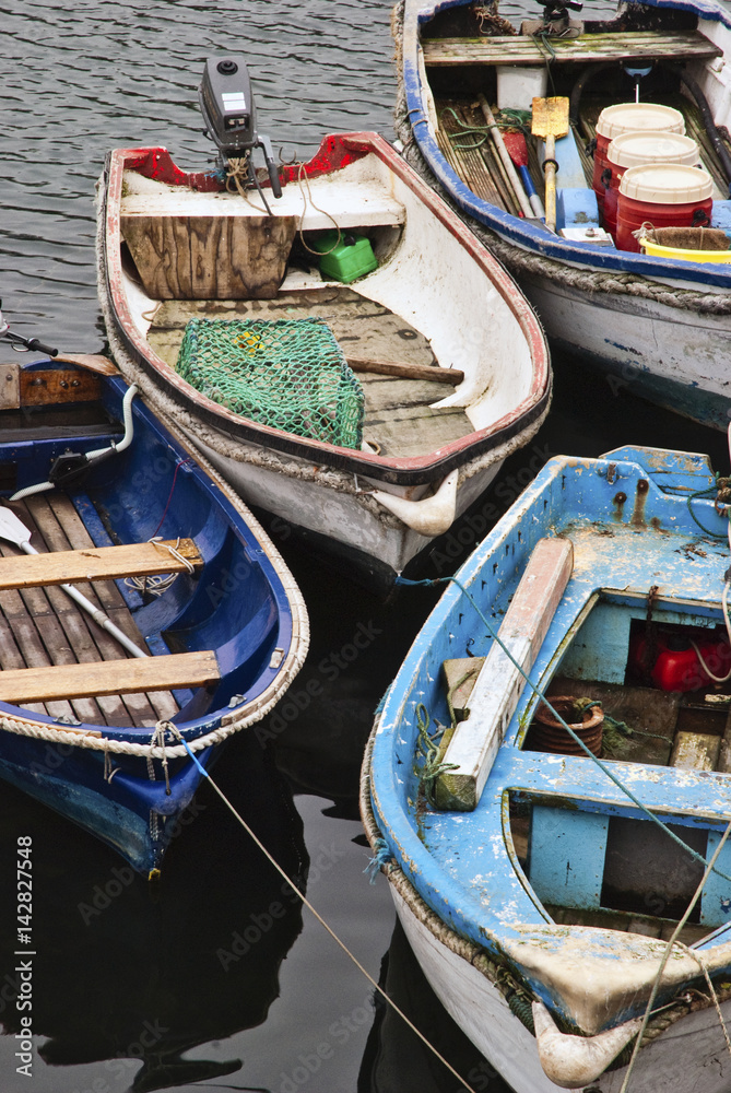 Rowing boats tied up at dock full of old ropes, tanks and other tools