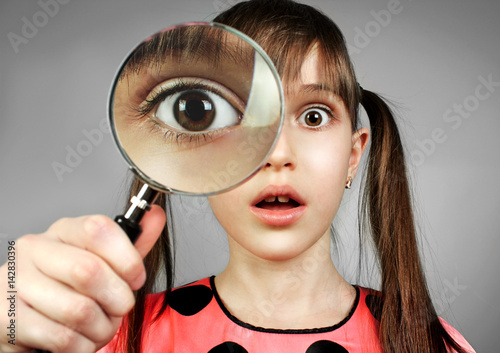 Φωτογραφία surprised child girl, searching  with magnifying glass