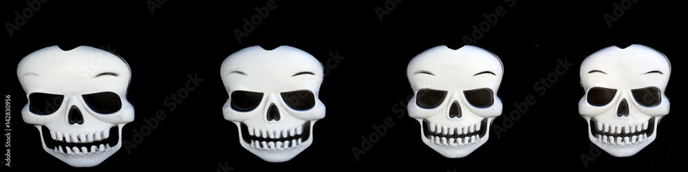 Fototapeta premium Four Halloween skulls on a black background. Horizontal.