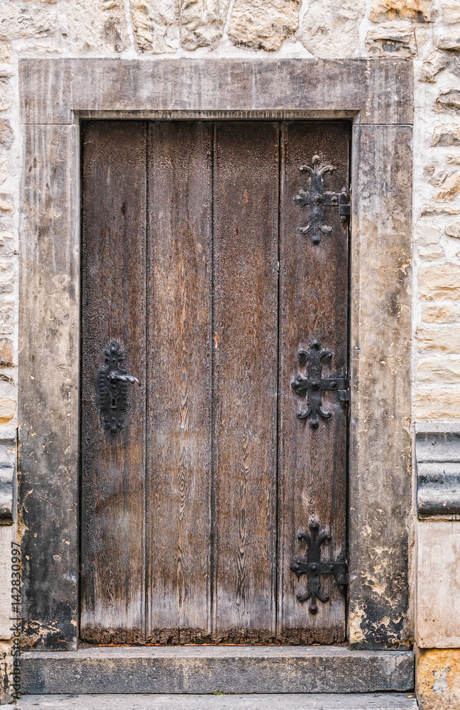 Ancient wooden door in old stone wall. Prague, Czech