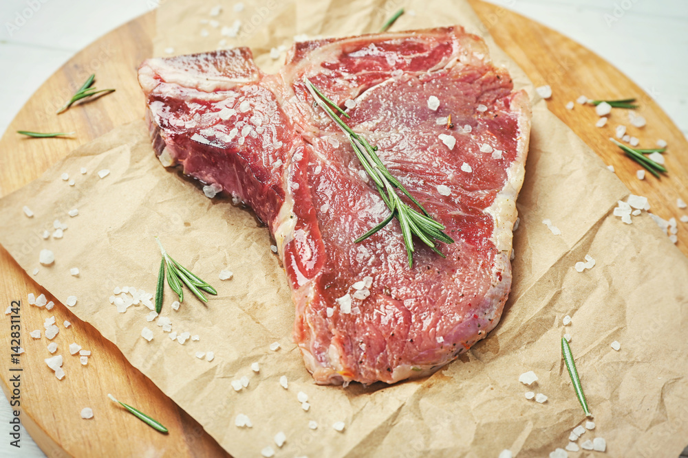 Seasoned steak with rosemary on parchment Seasoned steak with rosemary on parchment