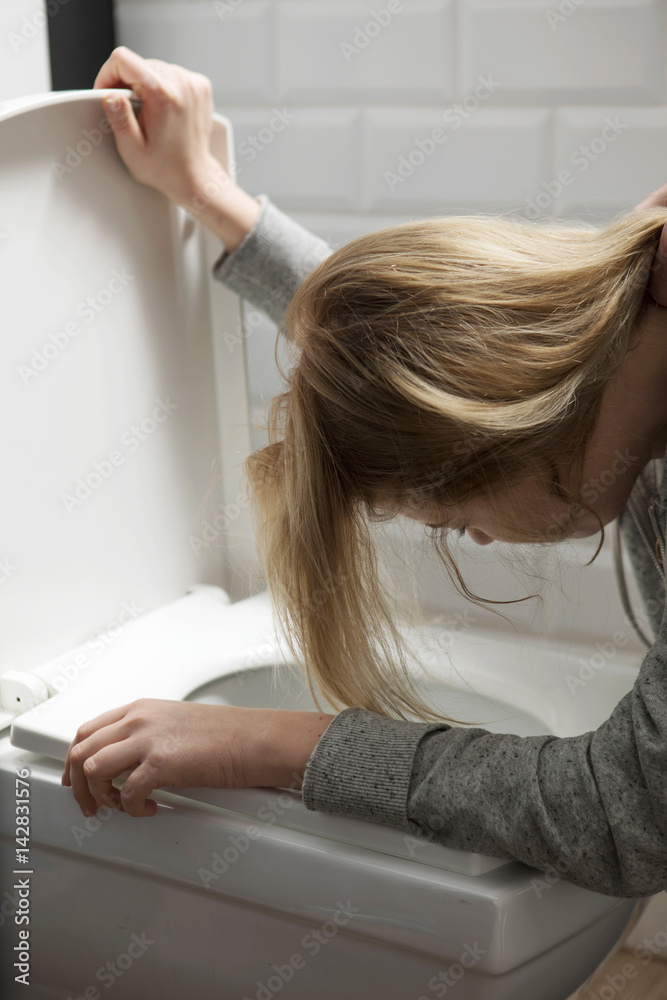 Man holding his girlfriend's hair while she is vomiting Stock Photo Adobe Stock