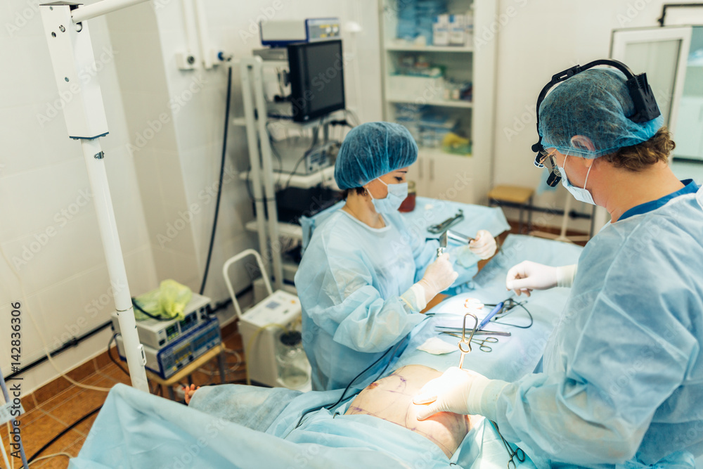 Surgeons team working with Monitoring of patient in surgical operating room. breast augmentation