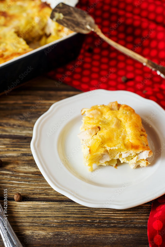 Useful, hearty and delicious dinner or lunch, potato casserole with chicken, cheese, mayonnaise, egg and spices on a wooden background 