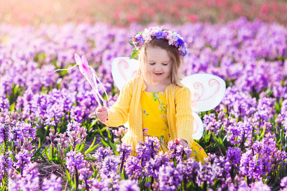 Little girl in fairy costume playing in flower field Little girl in fairy costume playing in flower field