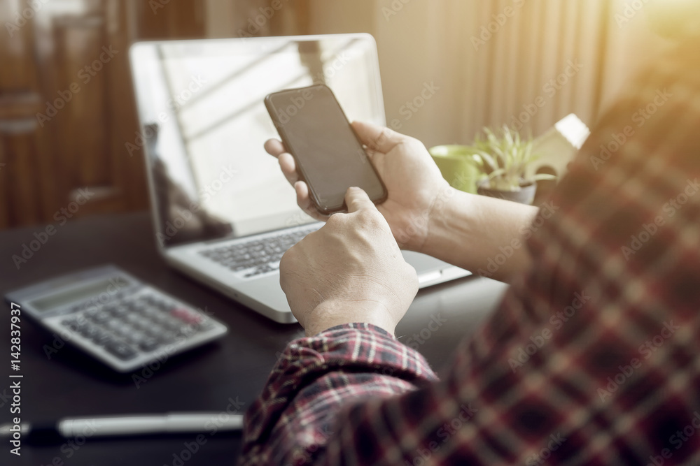 Obraz premium Side view shot of a man's hands using smart phone in interior, rear view of business man hands busy with tablets at office desk, young male student typing calculator at wooden table