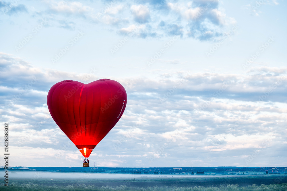Naklejka premium Red air balloon heart rises up at dawn