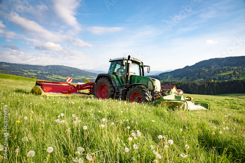 Fototapeta Nowoczesna technika rolnicza - rolnik kosi trawę na kiszonkę w Allgäu