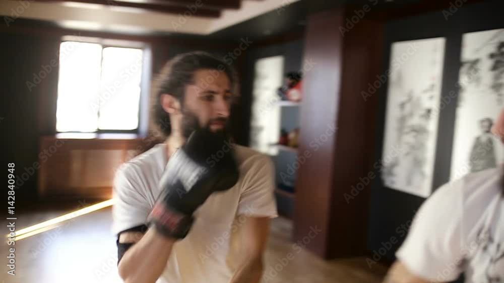 The twin brothers in boxing gloves sparring in the training hall. Chinese martial arts. The twin brothers in boxing gloves sparring in the training hall. Chinese martial arts.