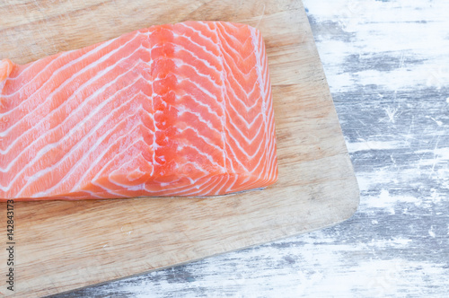 fresh raw uncooked salmon fish piece over wooden board  background