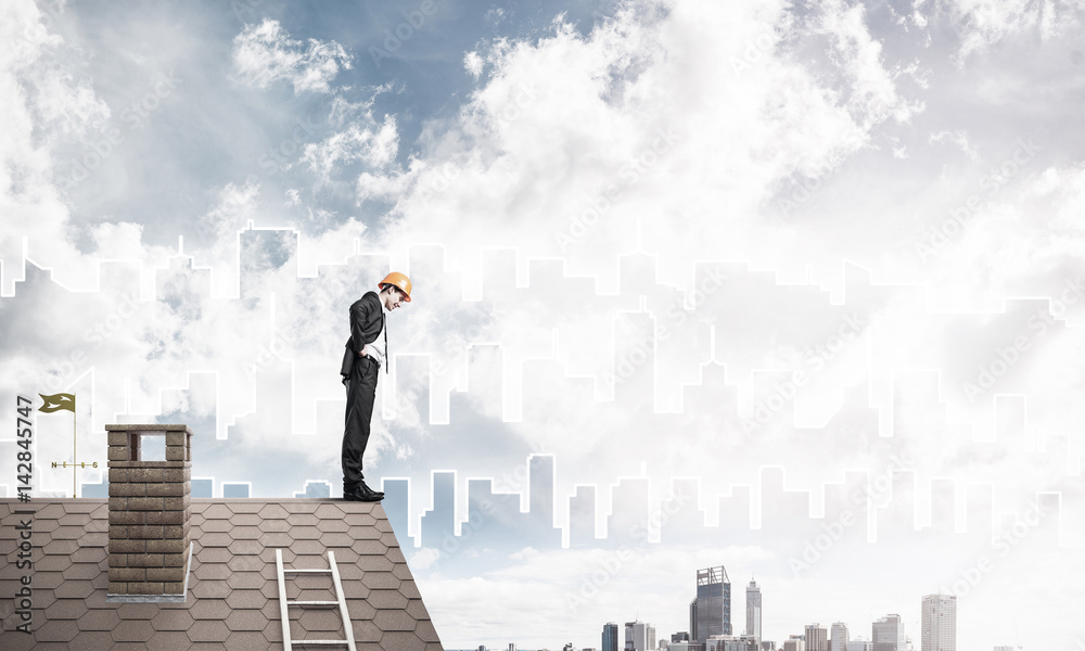 Engineer man standing on roof and looking down. Mixed media Engineer man standing on roof and looking down. Mixed media
