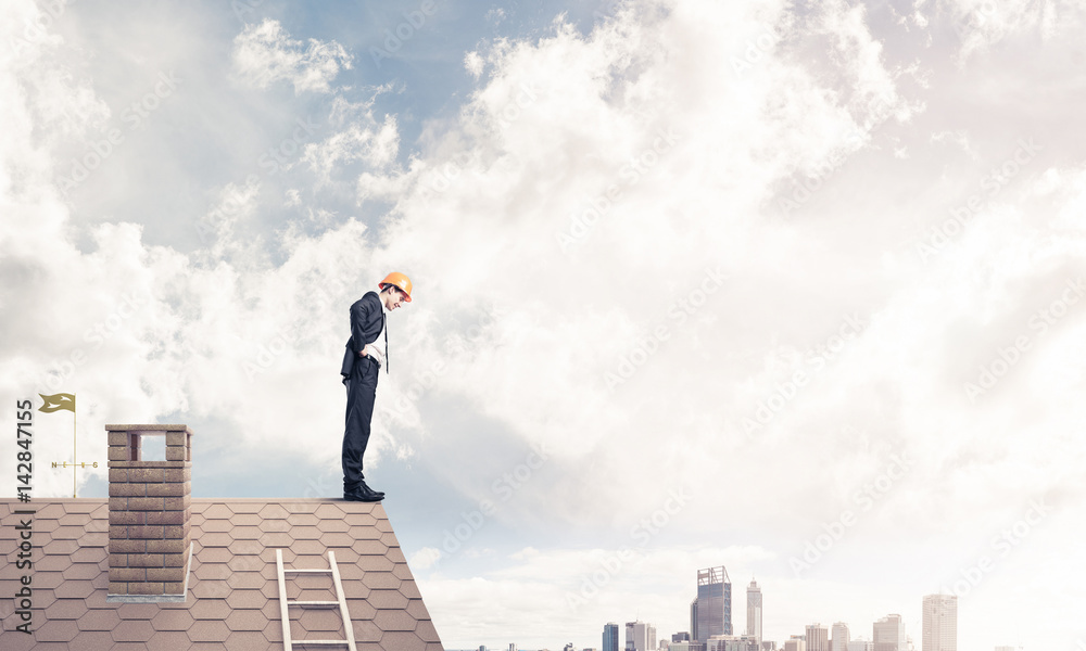Businessman looking down from roof and modern cityscape at backg Businessman looking down from roof and modern cityscape at backg