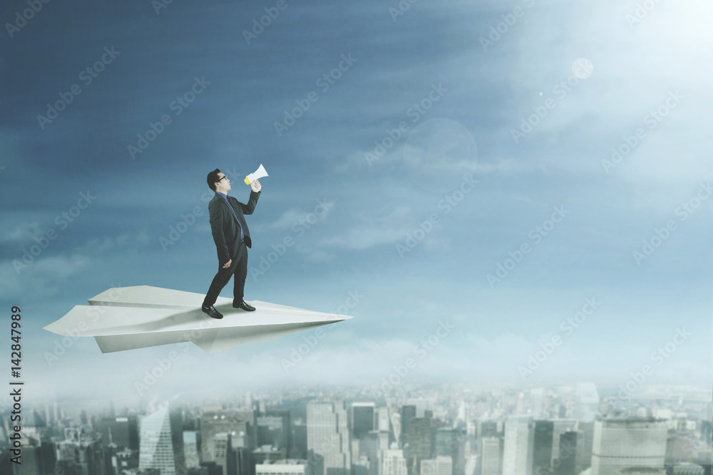 Businessman with megaphone on paper plane Businessman with megaphone on paper plane