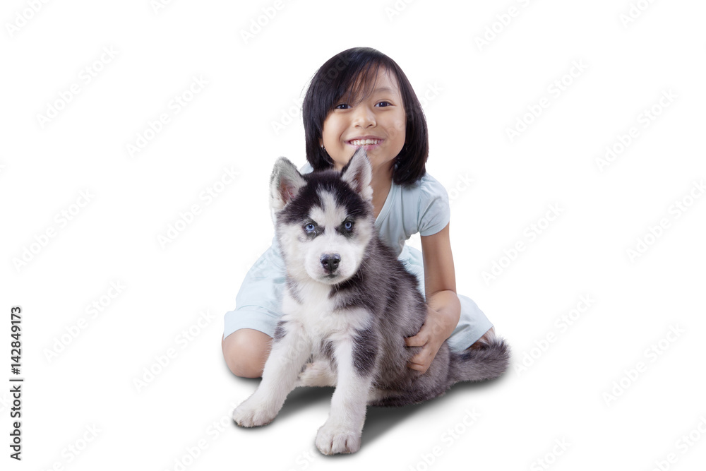 Cute girl plays with husky puppy on studio