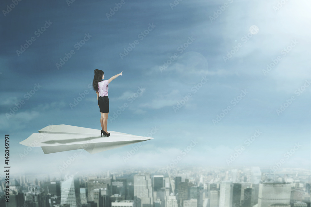Female entrepreneur stands on paper plane Female entrepreneur stands on paper plane