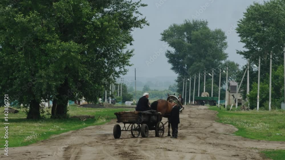 The old man on the cart communicates with the pedestrian The old man on the cart communicates with the pedestrian