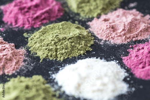 Various colorful superfood powders on dark background. Healthy food supplements, detox concept. Top view photo