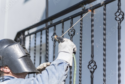 A worker welding metal handrails on the stairs. Ukraine.