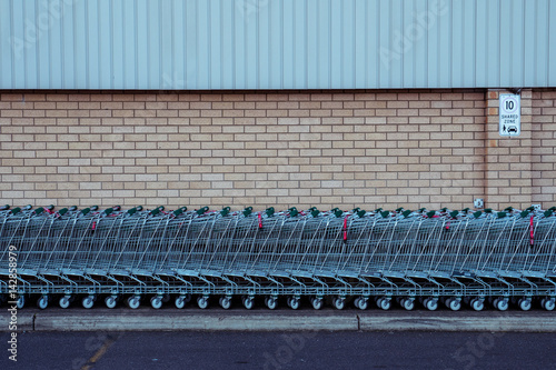 Row of trolleys parked against brick wall, shot front on with texture look