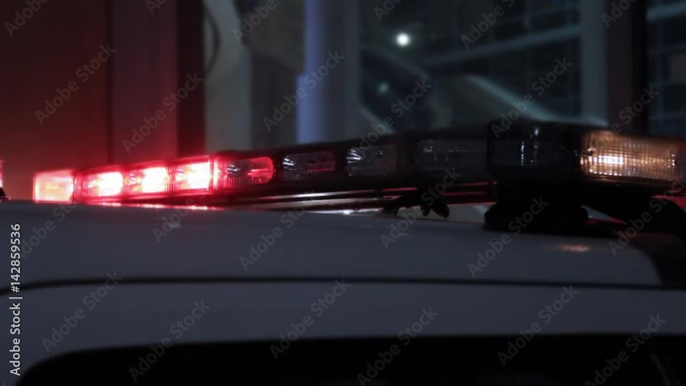 Emergency vehicle lights flashing red and yellow at a sporting event in the rain