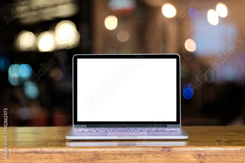 laptop blank screen on wooden table with bokeh background. Front view...