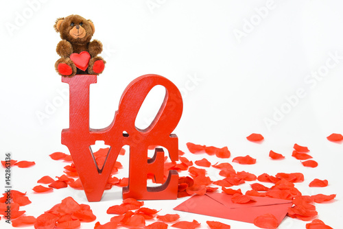 Hame made Love decor with red rose petals, a Valentine envelope  and a generic bargain store teddy holding a red satin heart photo